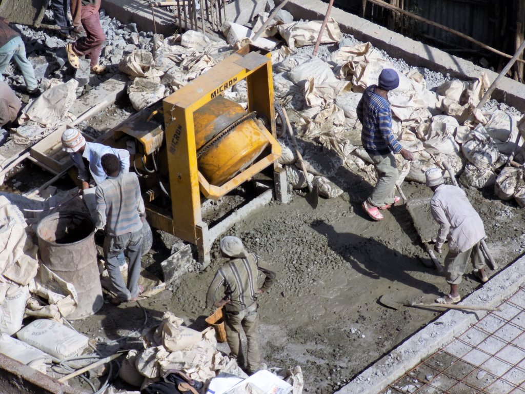 This photo shows builders working with hand tools in the blazing sun