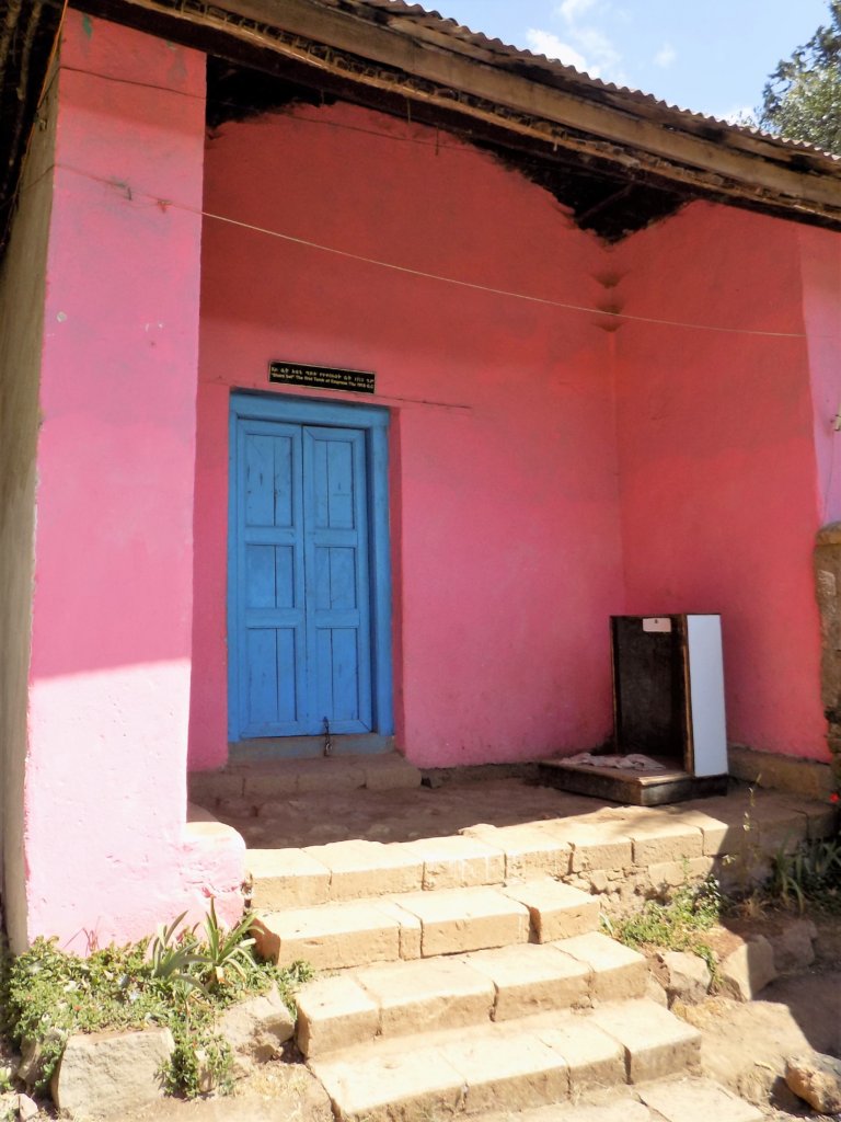 This photo shows the modest first tomb of Empress Titu, painted shocking pink with a vibrant blue door