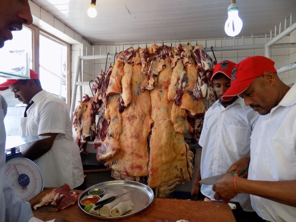 This photo shows the butcher's shop at the front of the restaurant with whole beef carcasses hanging up for people to choose from 