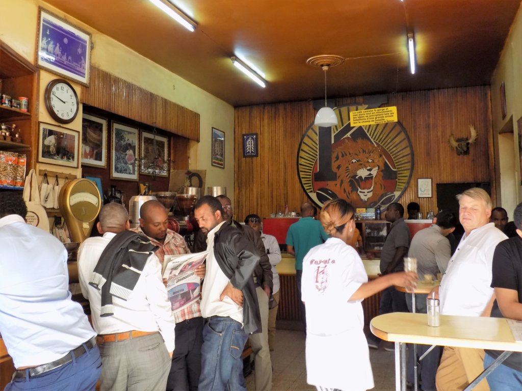 This photo shows lots of men standing drinking coffee in Tomoca coffee shop