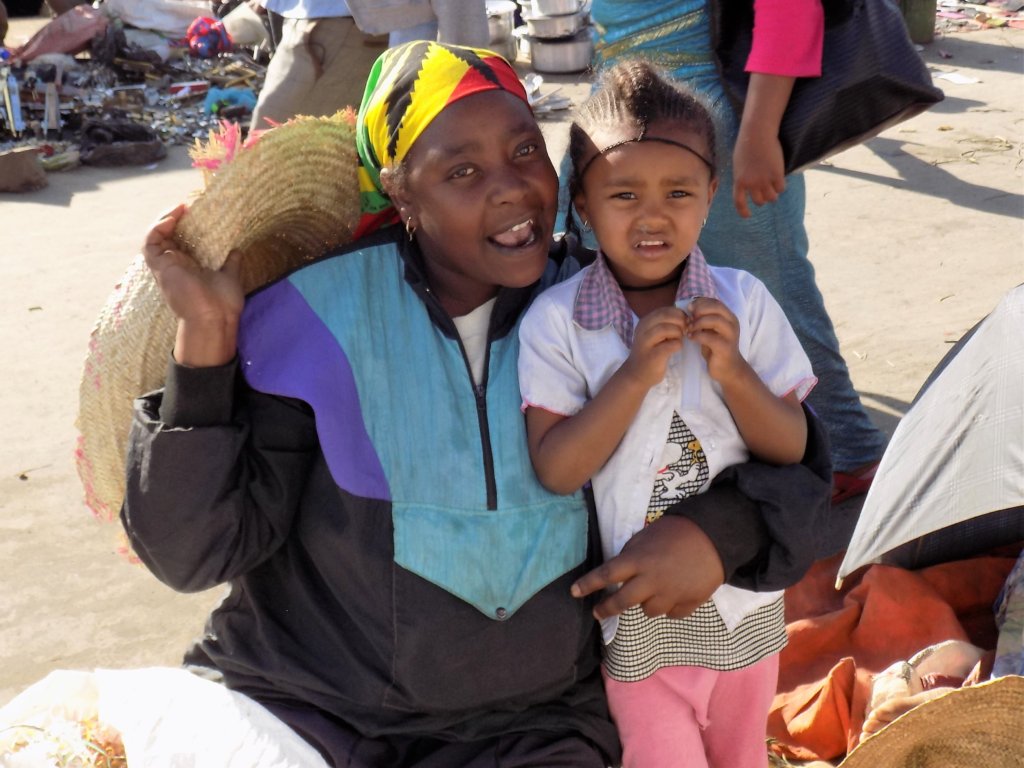 This photo shows a lady at the market with her young daughter. She was happy to pose for a picture.