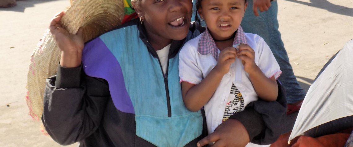 This photo shows a lady at the market with her young daughter. She was happy to pose for a picture.