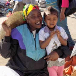 This photo shows a lady at the market with her young daughter. She was happy to pose for a picture.