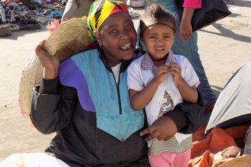 This photo shows a lady at the market with her young daughter. She was happy to pose for a picture.