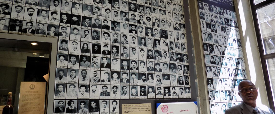 This photo shows Our guide in front of a wall of photos of victims of the Derg