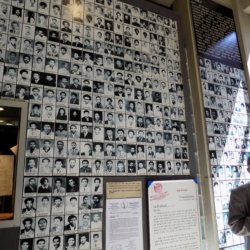 This photo shows Our guide in front of a wall of photos of victims of the Derg