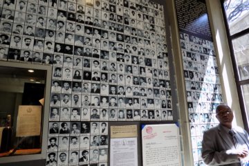 This photo shows Our guide in front of a wall of photos of victims of the Derg