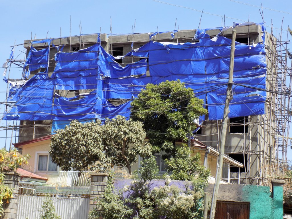 This picture shows a half-constructed office block in Addis Ababa with wooden scaffolding and tarpaulins all around it