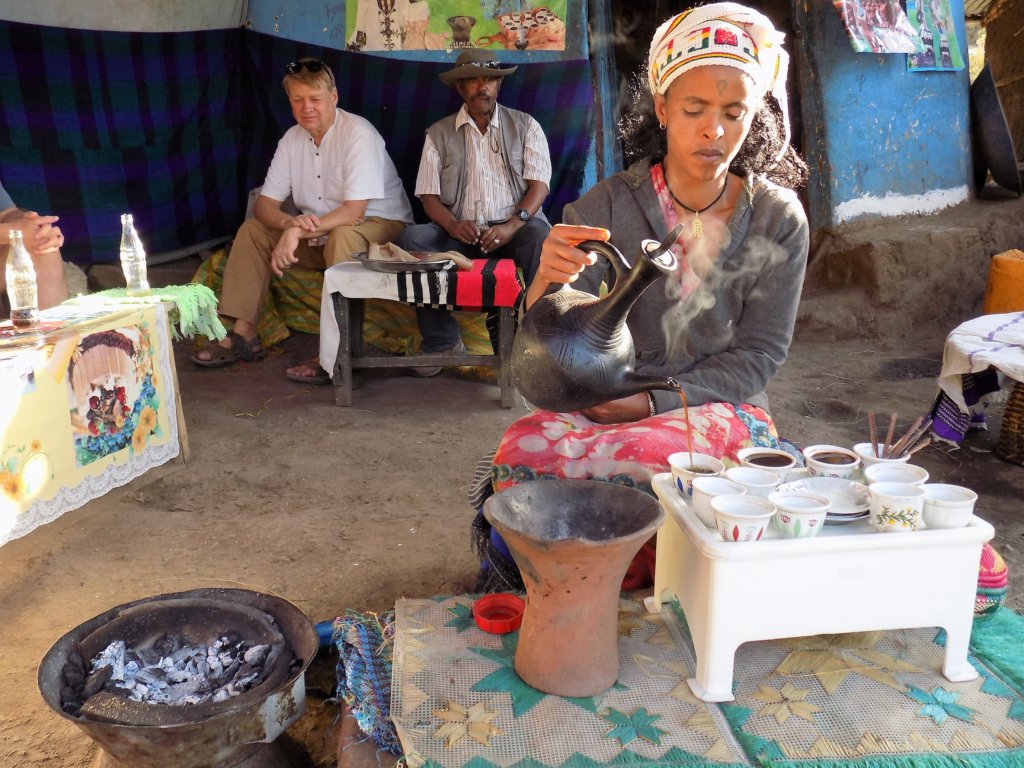 This photo shows a lady pouring coffee into small cups