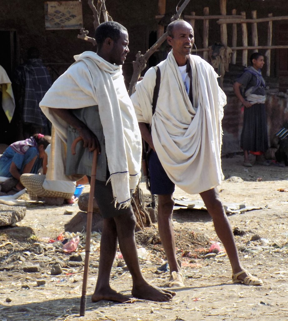 This photo shows two men in traditional dress standing in the street chatting
