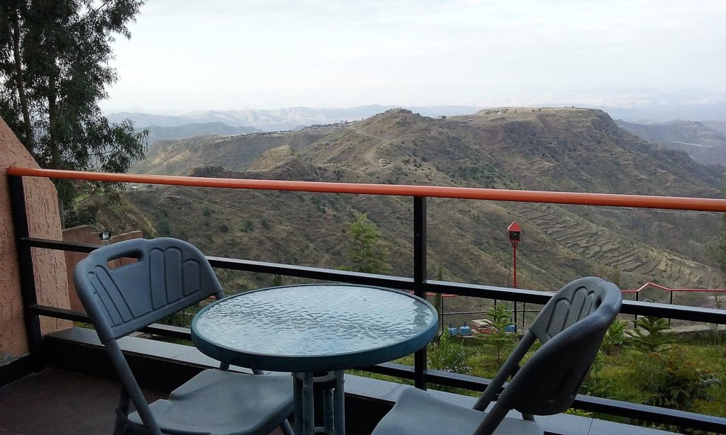 This photo shows our balcony with a small round glass table and two chairs and a spectacular view of the surrounding countryside