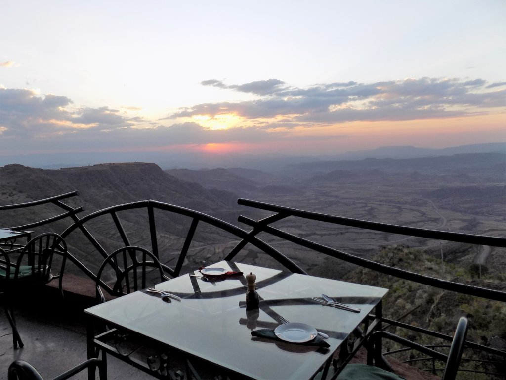 This photo shows a table and two chairs on one of the dining pods with the sun going down in the background