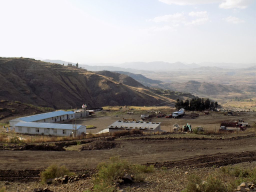 This photo shows a number of low-rise buildings erected in a valley between high mountains