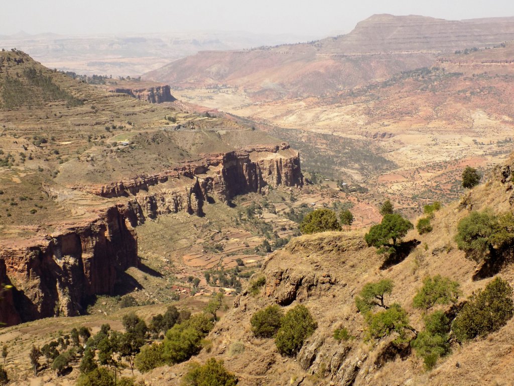 This photo shows spectacular mountains with steep cliffs dropping to a dry riverbed