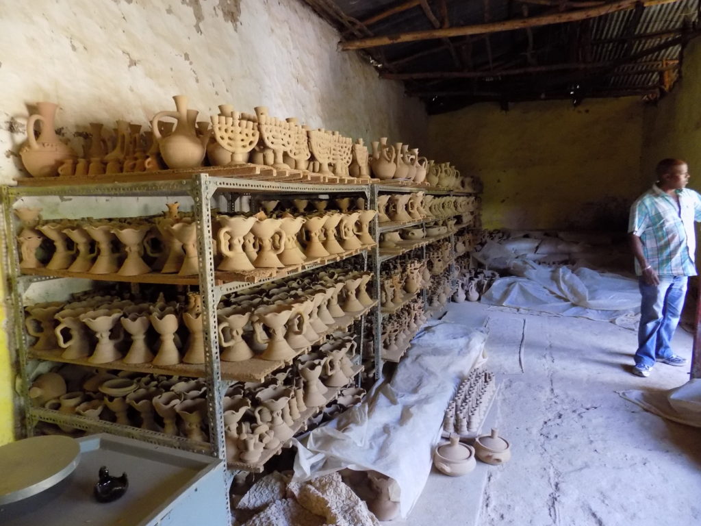 This photo shows shelves full of pots waiting to go into the kiln for firing