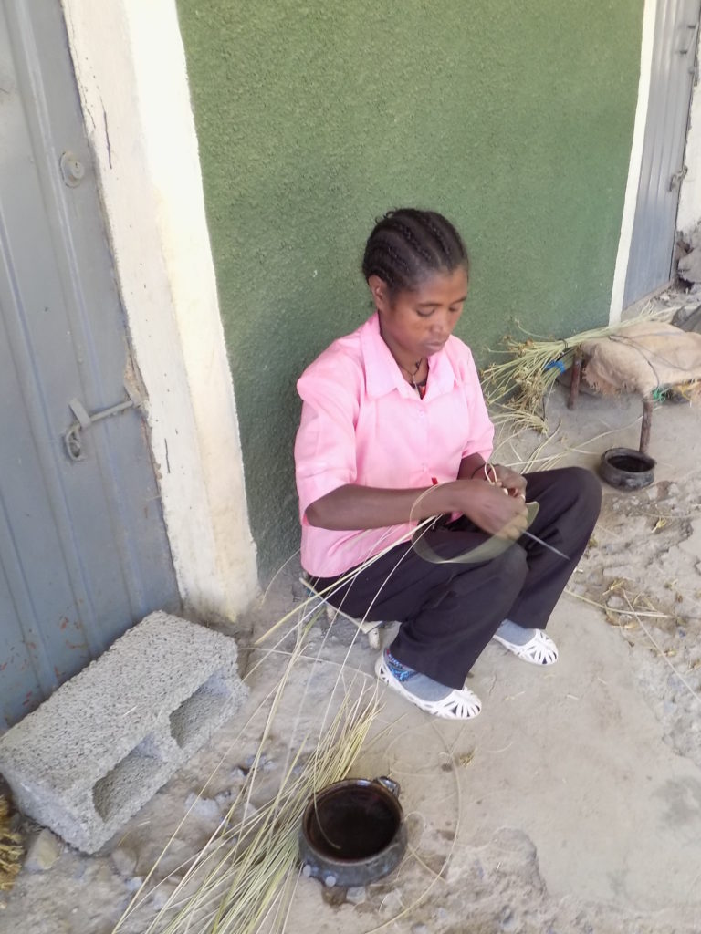 This photo shows a lady making a basket by hand