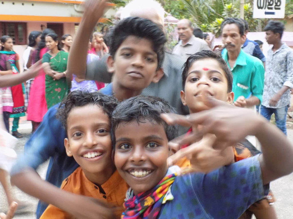 This photo shows a group of four local boys smiling and playing up to the camera