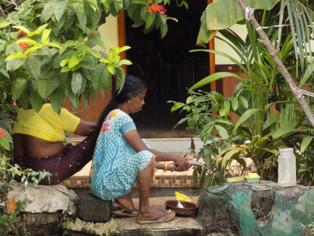 This photo shows a lady sitting at the side of a backwater preparing fish