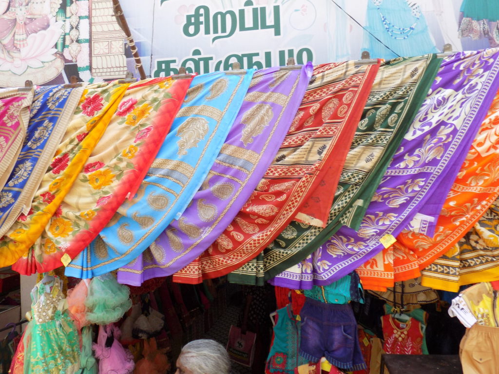 This picture shows vibrantly coloured saris hanging above a shop front.
