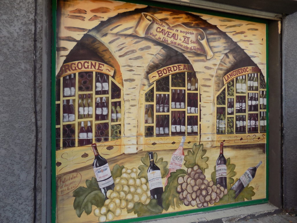 This photo shows a wine cellar full of wine bottles painted onto the outside of a shop in Marseillan.