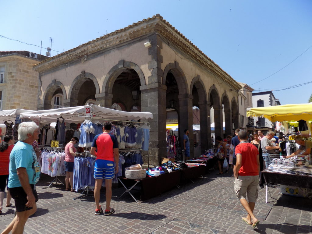 This picture shows the 17th century market hall in Marseillan on a brilliantly sunny day with colourful market stalls in the foreground.