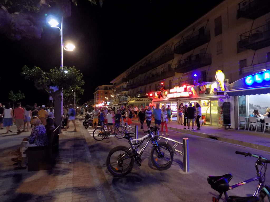 This photo shows lots of people walking along the promenade at Valras Plage during the evening