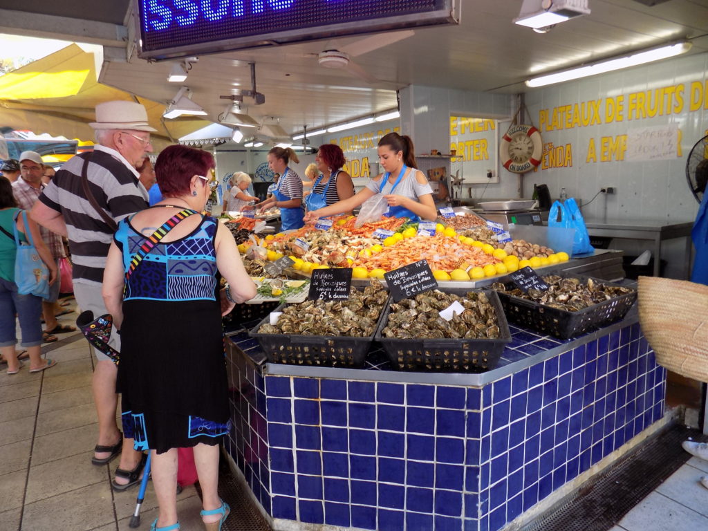 This photo shows the indoor fish market of Valras Plage with a stall full of oysters and prawns