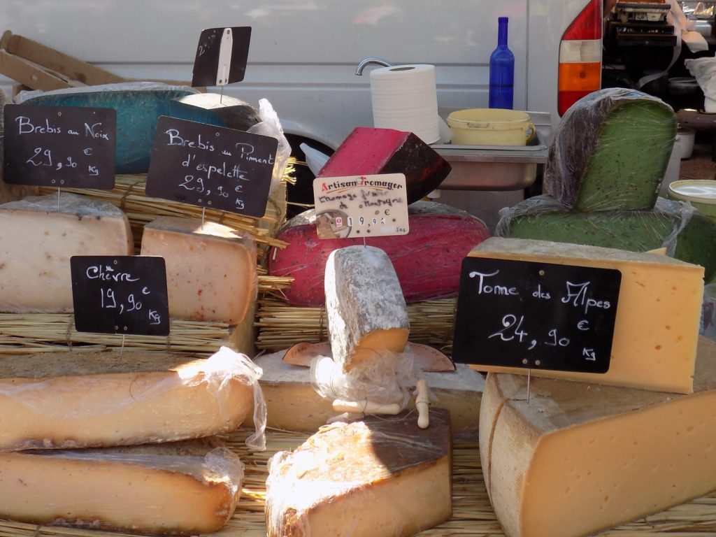 This photo shows a cheese stall on Valras market with colourful blue, red and green cheeses