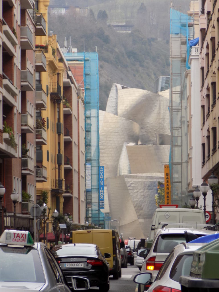 This photo shows a busy Bilbao street with lots of traffic and a view of the Guggenheim at the bottom.