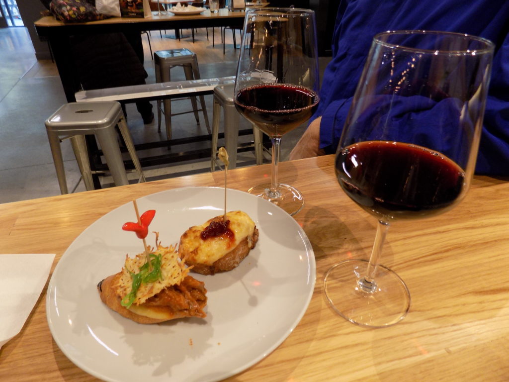 This photo shows a plate with two delicious pintxas and a glass of red wine