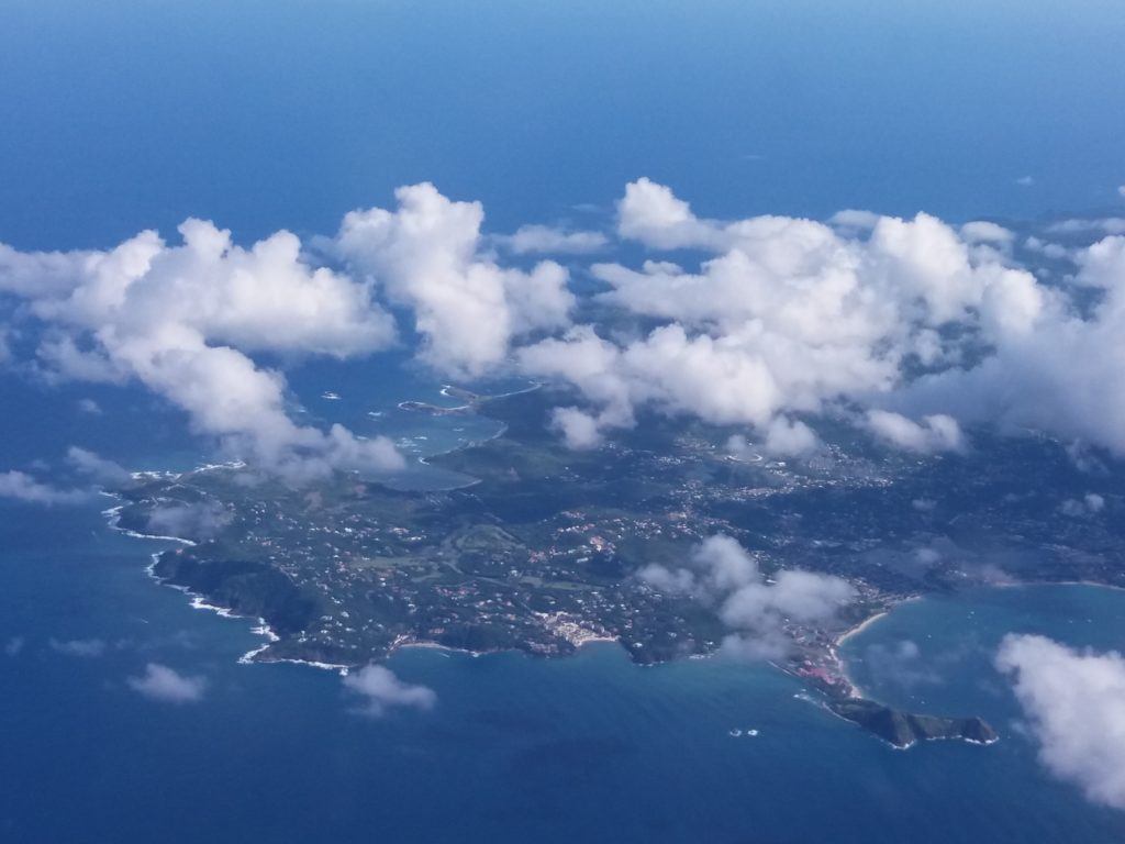 This image shows our first view of the island of Trinidad. It was taken from the window on our flight from London Gatwick to Port of Spain, Trinidad. There are some fluffy white clouds partially obscuring the view.