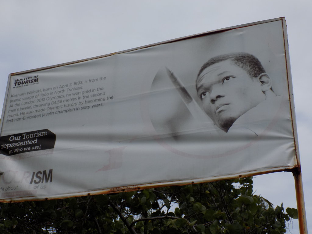 This picture shows a billboard celebrating the achievements of Keshorn Walcott. It has a photo of the athlete and a description of what he did.