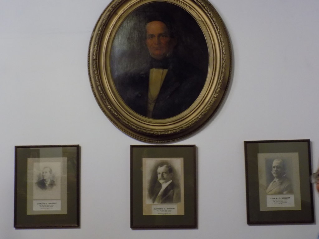This picture shows a painting of J G B Seigert with photos of his sons underneath