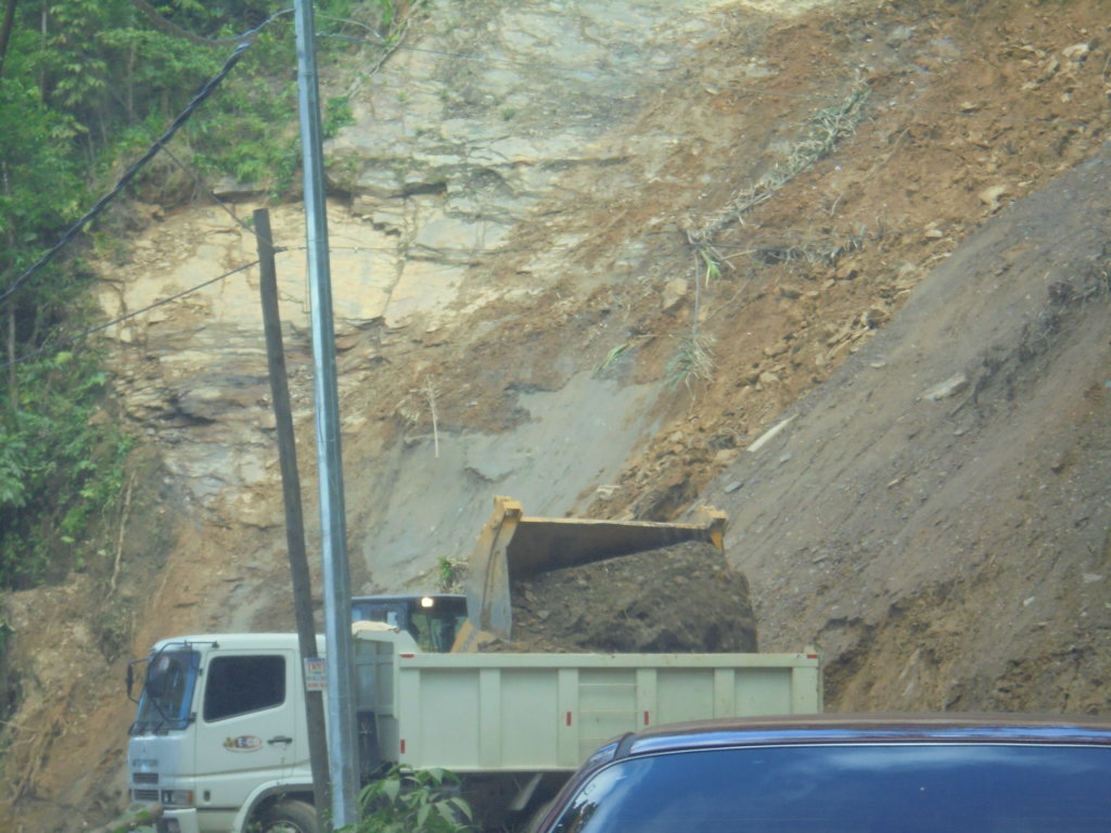 This photo shows a digger clearing fallen rocks and earth from the road in front of our car
