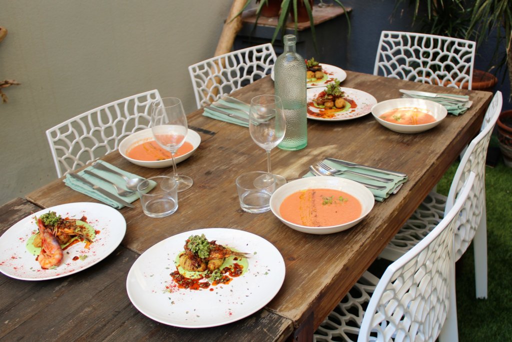 This picture shows a table set for four with gazpacho soup for a starter and fish for entree.