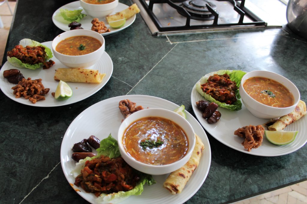 This picture shows four plates, each with a bowl of soup and a salad accompaniment.
