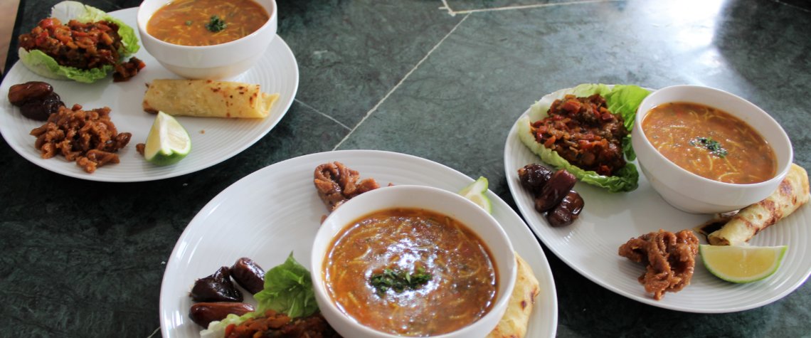 This picture shows four plates, each with a bowl of soup and a salad accompaniment.