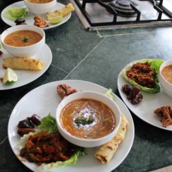 This picture shows four plates, each with a bowl of soup and a salad accompaniment.
