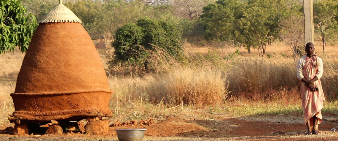 This picture shows a man standing a little way away from a conical grain store