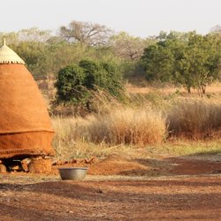 This picture shows a man standing a little way away from a conical grain store