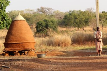 This picture shows a man standing a little way away from a conical grain store
