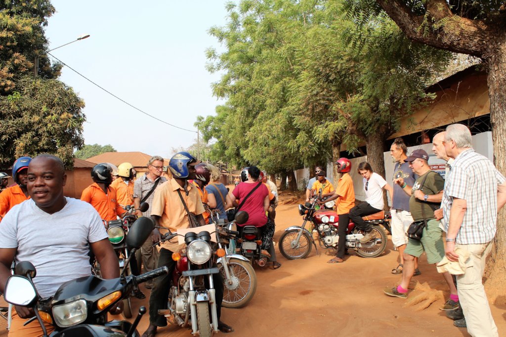 THis photo shows our tour group getting on the backs of moto-taxis for a tour of Abomey