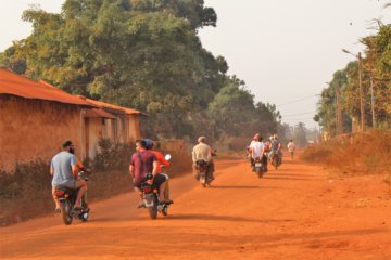 This photo shows some members of our group riding pillion along a red, dusty road