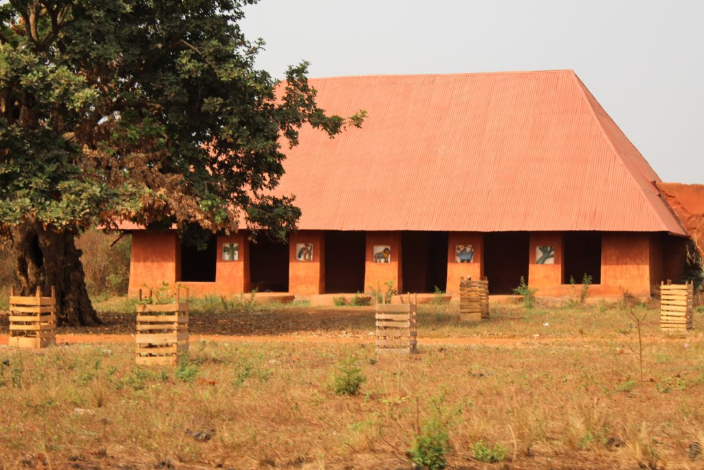 This photo shoes a low earthen building with a red roof