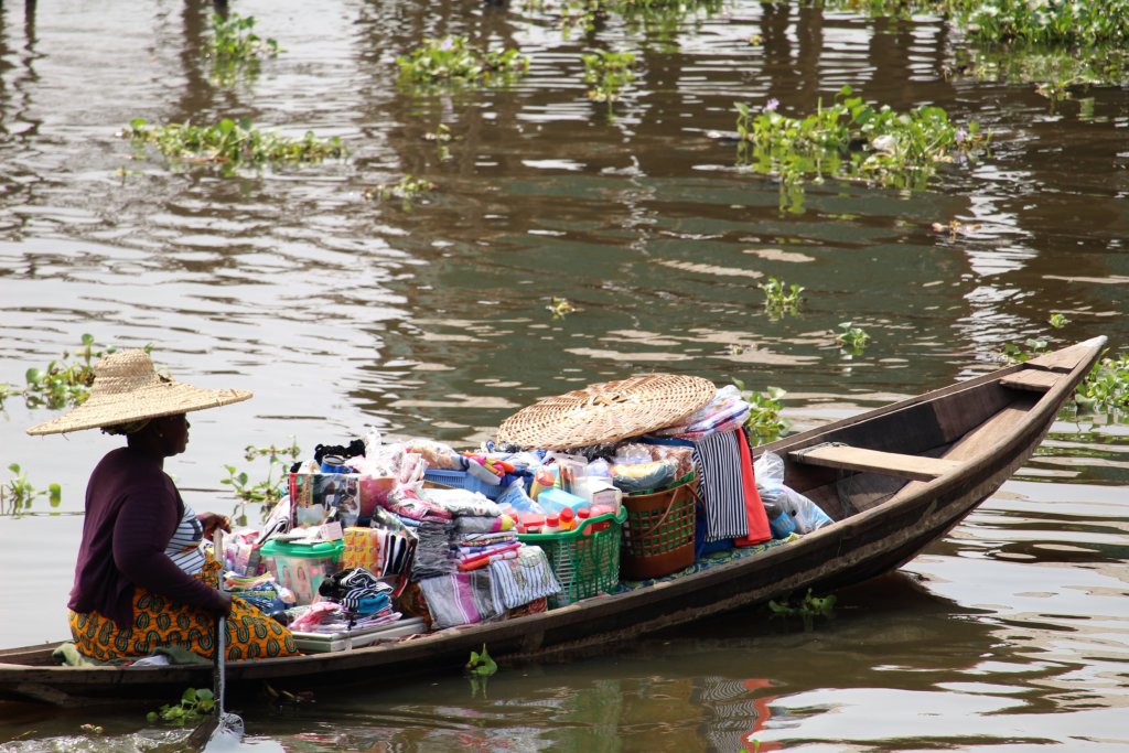 This photo shows a lady with her boat full of goods to sell at market