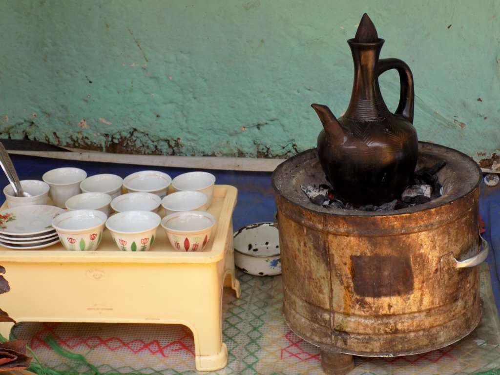 This picture shows a coffee pot heating on a charcoal stove and a number of handleless porcelain cups