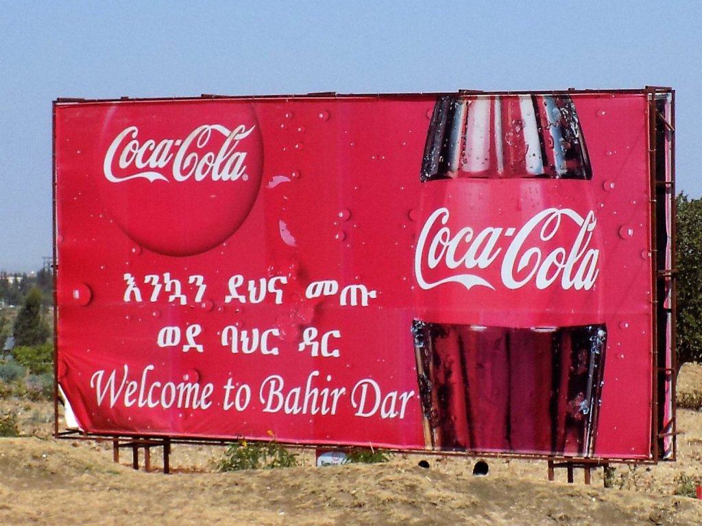 This photo shows a large metal sign by the roadside at the entrance to the city of Bahir Dar. It bears the slogan 'Welcome to Bahir Dar' and a large picture of a bottle of Coca-Cola