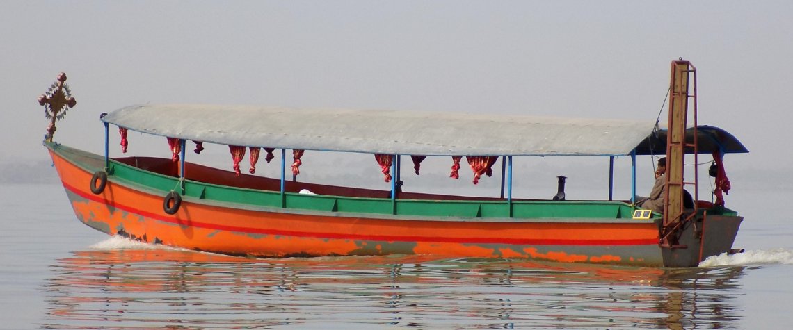 This photo shows an orange and green motor boat on Lake Tana