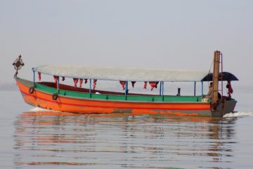 This photo shows an orange and green motor boat on Lake Tana