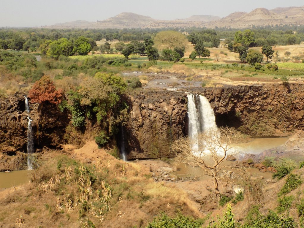 This photo shows a wide view of the Blue Nile Falls with the mountains in the background